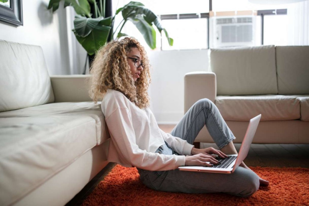 Zufriedene Kundin sitzt im Wohnzimmer am Rechner dank Corning Clear-Track